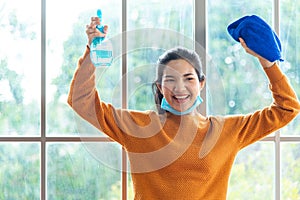 Smiling and happy young woman wearing medical mask and holding cleaning house equipment