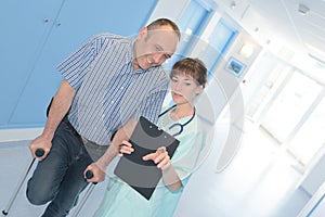 Smiling healthcare worker talking with man with crutches