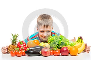 Smiling healthy boy with a bunch of juicy ripe vegetables and fruits on a white