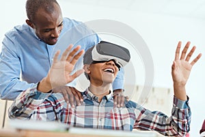 Smiling high school teenage student using virtual reality headset and teacher holding