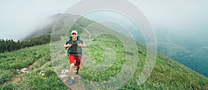 Smiling hiker man walking by the foggy cloudy weather mountain range path with backpack. Active sport backpacking healthy
