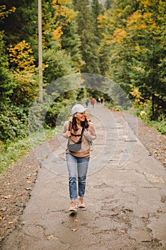 smiling hiker woman walking by autumn forest road