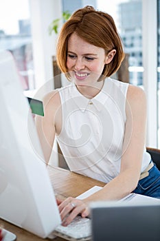 smiling hipster business woman inputting her credit card details