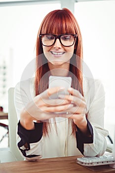 Smiling hipster businesswoman texting on her smartphone