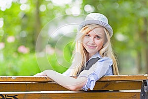 Smiling hipster girl sitting on bench in the city park