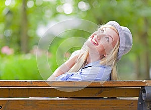 Smiling hipster girl sitting on bench in the city park