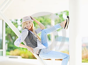 Smiling hipster girl sitting on urban structure