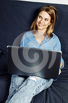 Smiling hipster girl talking with friends via an app on laptop, cheerful female student studying via portable computer.