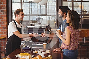 Smiling hipster giving credit card to barista