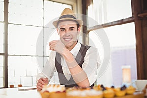 Smiling hipster sitting next to treats