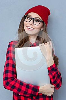 Smiling hipster woman holding laptop computer