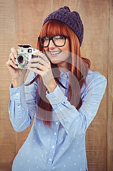 Smiling hipster woman taking pictures with a retro camera