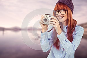 Smiling hipster woman taking pictures with a retro camera