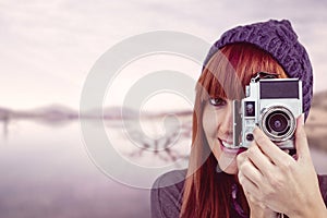 Smiling hipster woman taking pictures with a retro camera
