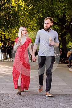 Smiling hipsters couple eating ice cream and having fun in the city. stylish young man with beard and blonde woman in