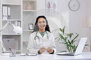 Smiling Hispanic female doctor with stethoscope in office