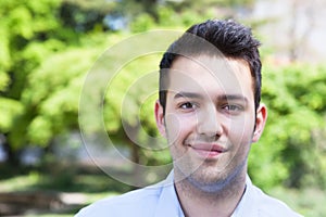 Smiling hispanic guy in a blue shirt outside in a park