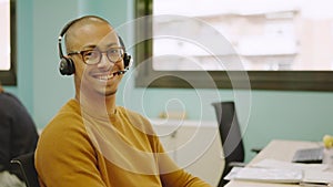 Smiling hispanic man using headset while working in a coworking