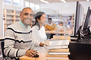 Smiling Hispanic man working on computer in library