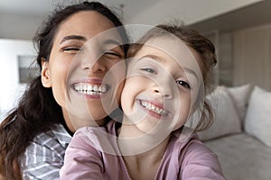 Smiling Hispanic mom and daughter make selfie together
