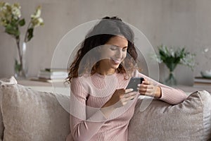 Smiling Hispanic woman relax at home using cellphone