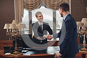 Smiling hotel receptionist helping Businessman to check in and receive key from room