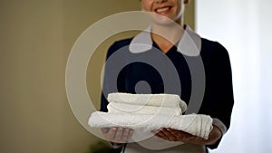 Smiling hotel worker showing clean pillows, good housekeeping, health standard