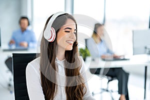 Smiling hotline operator woman with headset using computer in office.