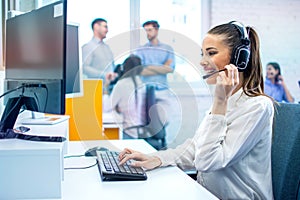 Smiling hotline operator woman with headset using computer in office