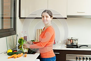 Smiling housewife washing vegetables