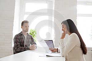 Smiling hr reading resume at job interview with serious candidat