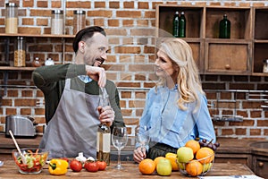 smiling husband opening wine bottle with corkscrew and looking