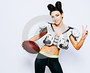 Smiling incredibly beautiful, athletic brunette girl in a shoulderpads and an American football helmet demonstrating