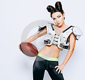 Smiling incredibly beautiful, athletic brunette girl in a shoulderpads and an American football helmet demonstrating