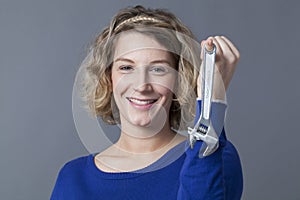 Smiling independent mechanics girl holding wrench for self-automotive repair