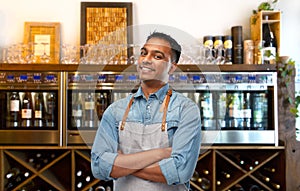 Smiling indian barman or waiter in apron at bar