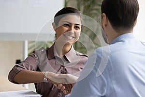 Smiling indian businesswoman handshake colleague at briefing