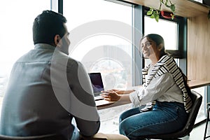 Smiling indian coworkers discussing business details while sitting in office