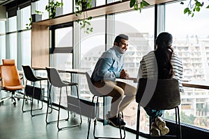 Smiling indian coworkers discussing business details while sitting in office