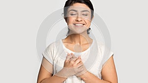 Smiling indian girl hold hands at chest feel grateful