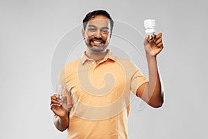 Smiling indian man comparing different light bulbs