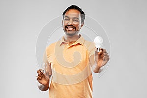 Smiling indian man comparing different light bulbs