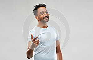 Smiling indian man pointing finger at you