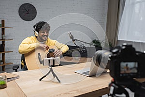 Smiling indian podcaster in headphones holding