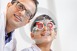 Smiling Indian-thai boy choosing glasses in optics store, Boy doing eye test checking examination with optometrist using trial
