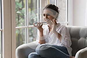 Smiling Indian woman holds smartphone talking on speakerphone