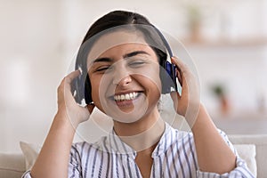 Smiling Indian woman listen to music in headphones