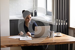 Smiling Indian woman pay taxes online on laptop