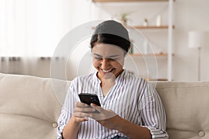 Smiling Indian woman relax at home using smartphone