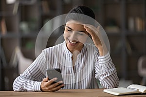 Smiling Indian woman use cellphone texting laughing